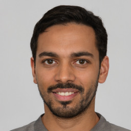 Joyful latino young-adult male with short  black hair and brown eyes