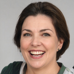 Joyful white adult female with medium  brown hair and green eyes