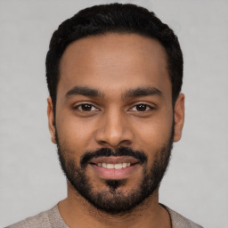 Joyful black young-adult male with short  black hair and brown eyes