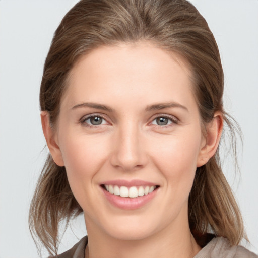 Joyful white young-adult female with medium  brown hair and grey eyes