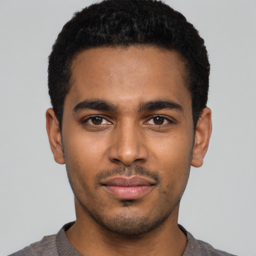 Joyful black young-adult male with short  black hair and brown eyes