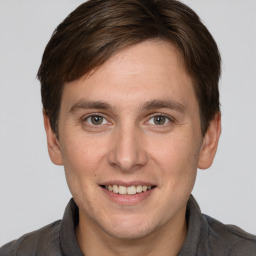 Joyful white young-adult male with short  brown hair and grey eyes