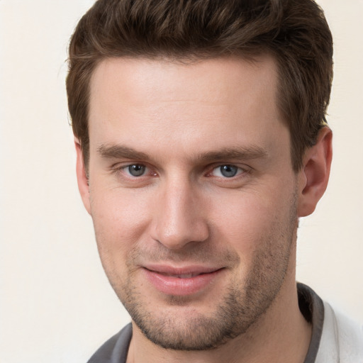 Joyful white young-adult male with short  brown hair and grey eyes