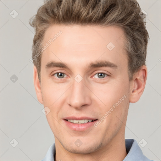 Joyful white young-adult male with short  brown hair and grey eyes