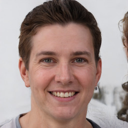 Joyful white young-adult male with short  brown hair and grey eyes