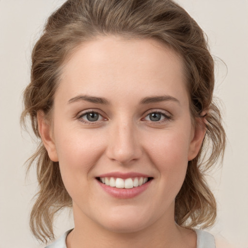 Joyful white young-adult female with medium  brown hair and grey eyes