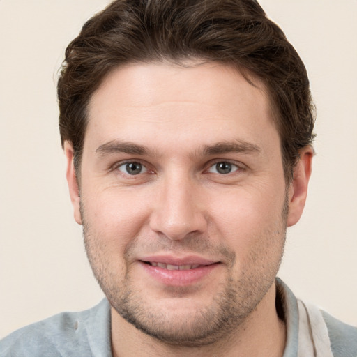 Joyful white young-adult male with short  brown hair and grey eyes