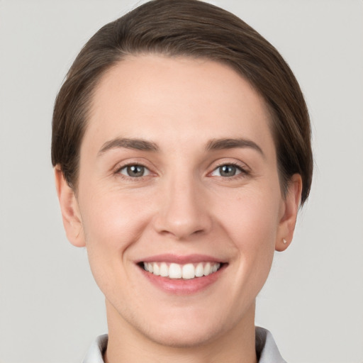 Joyful white young-adult female with short  brown hair and grey eyes