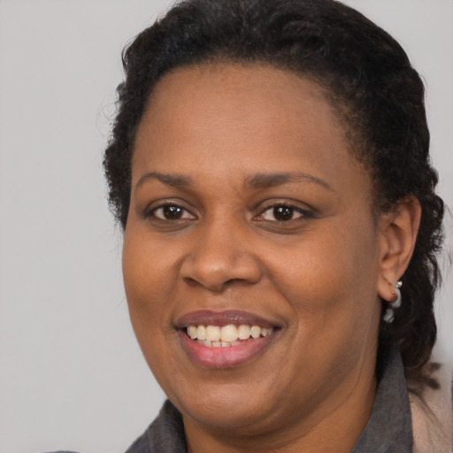 Joyful black adult female with long  brown hair and brown eyes