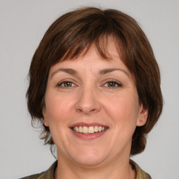 Joyful white adult female with medium  brown hair and green eyes