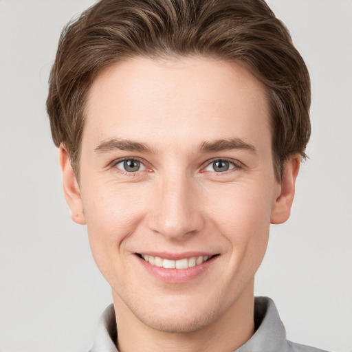 Joyful white young-adult male with short  brown hair and grey eyes