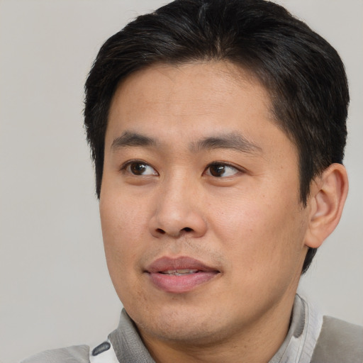 Joyful asian young-adult male with short  brown hair and brown eyes