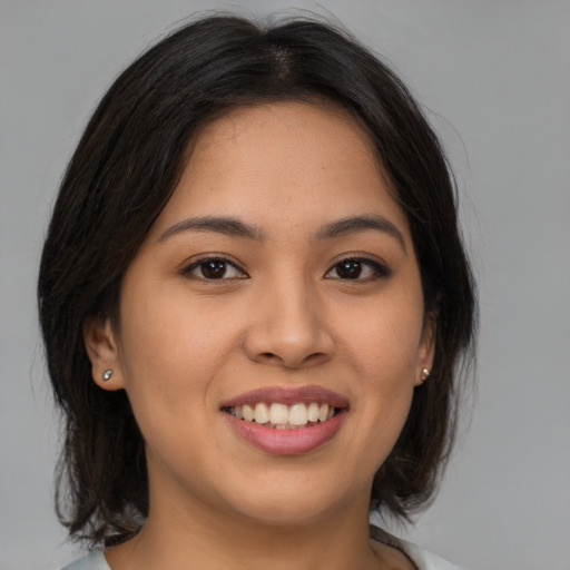 Joyful latino young-adult female with medium  brown hair and brown eyes