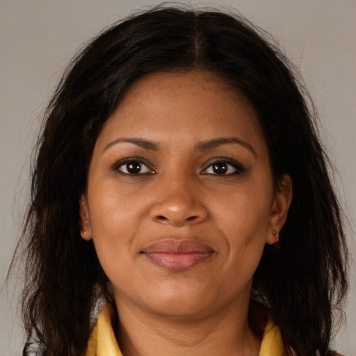 Joyful black young-adult female with long  brown hair and brown eyes