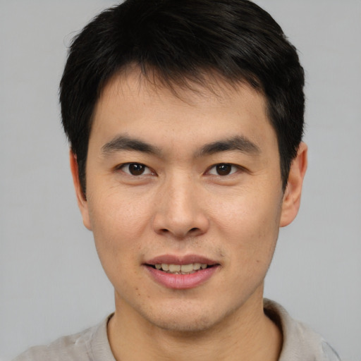 Joyful asian young-adult male with short  black hair and brown eyes