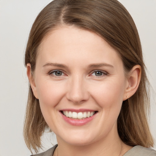 Joyful white young-adult female with medium  brown hair and grey eyes