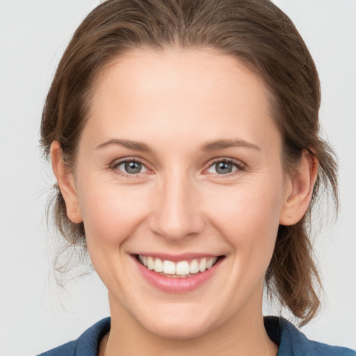 Joyful white young-adult female with medium  brown hair and grey eyes