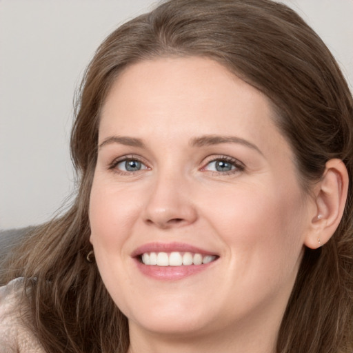 Joyful white young-adult female with long  brown hair and grey eyes