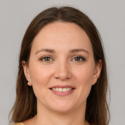 Joyful white adult female with long  brown hair and grey eyes