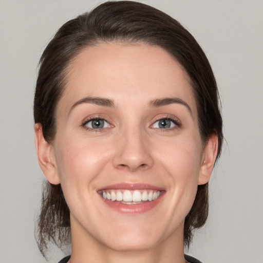 Joyful white young-adult female with medium  brown hair and grey eyes