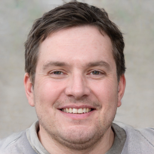 Joyful white adult male with short  brown hair and grey eyes