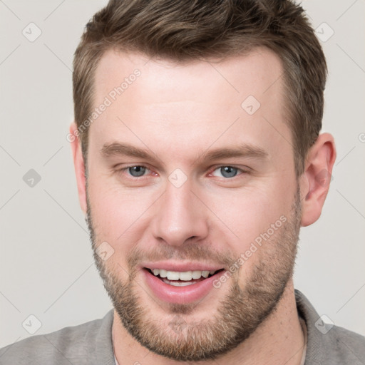 Joyful white young-adult male with short  brown hair and grey eyes