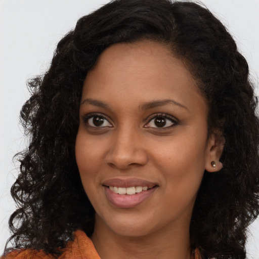 Joyful black young-adult female with long  brown hair and brown eyes