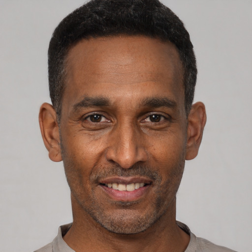 Joyful black adult male with short  black hair and brown eyes
