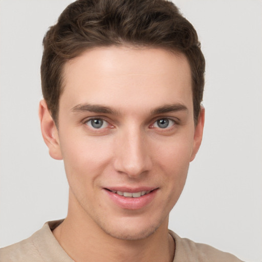 Joyful white young-adult male with short  brown hair and grey eyes