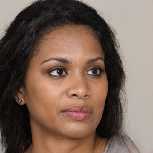 Joyful black young-adult female with long  brown hair and brown eyes