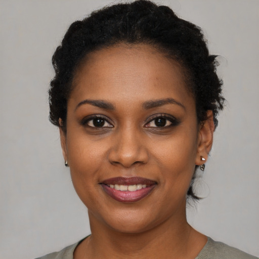 Joyful black young-adult female with short  black hair and brown eyes