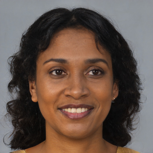 Joyful black young-adult female with long  brown hair and brown eyes