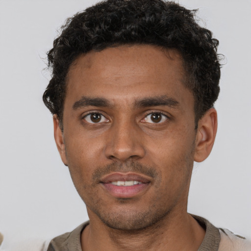 Joyful black young-adult male with short  brown hair and brown eyes