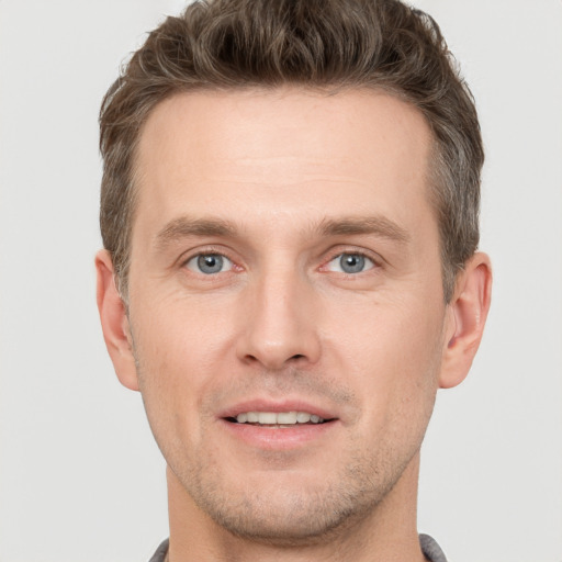 Joyful white young-adult male with short  brown hair and grey eyes