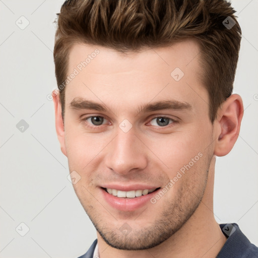 Joyful white young-adult male with short  brown hair and grey eyes