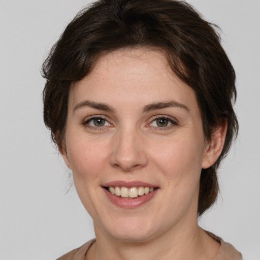 Joyful white young-adult female with medium  brown hair and green eyes