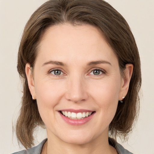 Joyful white young-adult female with medium  brown hair and grey eyes