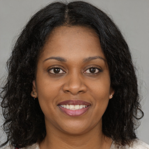 Joyful black young-adult female with long  brown hair and brown eyes