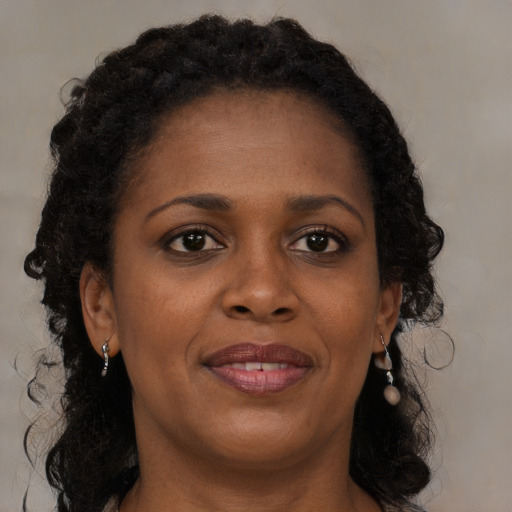 Joyful black young-adult female with long  brown hair and brown eyes