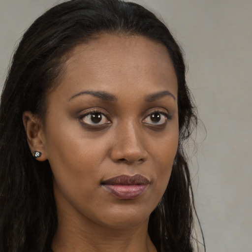 Joyful black young-adult female with long  brown hair and brown eyes