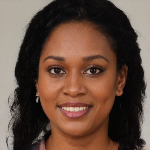 Joyful black young-adult female with long  black hair and brown eyes