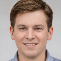 Joyful white young-adult male with short  brown hair and grey eyes