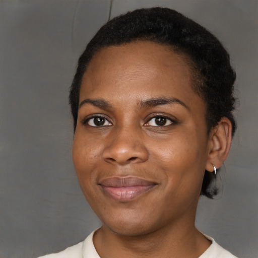 Joyful black young-adult female with short  black hair and brown eyes