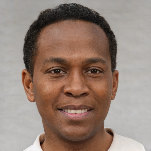 Joyful black young-adult male with short  brown hair and brown eyes