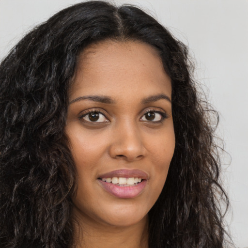 Joyful black young-adult female with long  brown hair and brown eyes