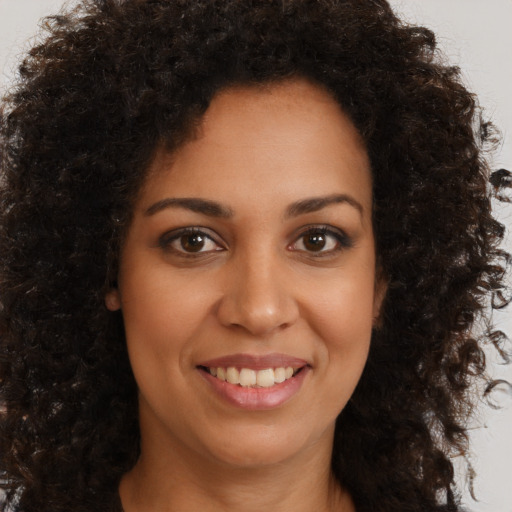 Joyful black young-adult female with long  brown hair and brown eyes