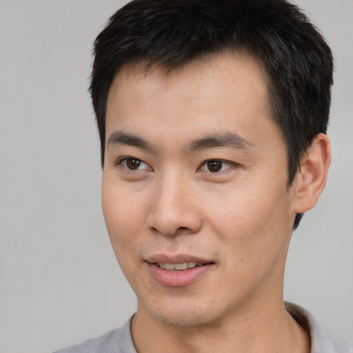 Joyful asian young-adult male with short  brown hair and brown eyes