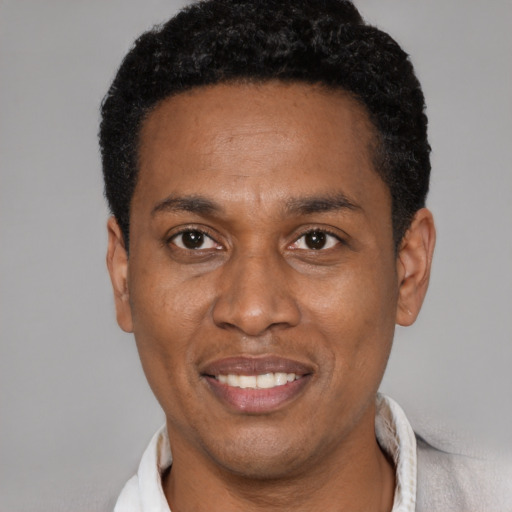 Joyful black adult male with short  black hair and brown eyes