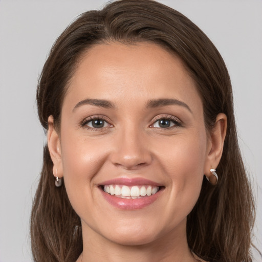 Joyful white young-adult female with long  brown hair and grey eyes