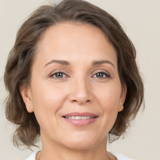 Joyful white adult female with medium  brown hair and grey eyes